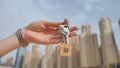 The concept of buying an apartment. Girl holds the keys to a new house against the backdrop of skyscrapers in the city. Royalty Free Stock Photo