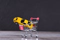 Concept of buying a new car. Toy car in shopping basket on wooden background Royalty Free Stock Photo
