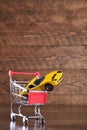 Concept of buying a new car. Toy car in shopping basket on wooden background Royalty Free Stock Photo