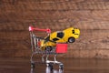 Concept of buying a new car. Toy car in shopping basket on wooden background Royalty Free Stock Photo