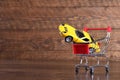 Concept of buying a new car. Toy car in shopping basket on wooden background Royalty Free Stock Photo