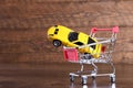 Concept of buying a new car. Toy car in shopping basket on wooden background Royalty Free Stock Photo