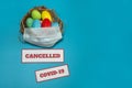 A medical mask, a nest with colorful Easter eggs and warning signs on a light blue background. Royalty Free Stock Photo