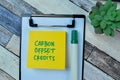 Concept of Carbon Offset Credits write on sticky notes isolated on Wooden Table