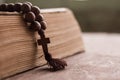 Wooden prayer beads with a Christian cross lie on the holy bible book on a wooden background. Royalty Free Stock Photo