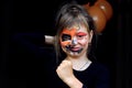 The concept of celebrating the autumn holiday Halloween. A cheerful eight-year-old girl, painted with black and orange colors Royalty Free Stock Photo