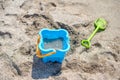 The concept of children`s holiday at the sea. Children`s toys on the sand: blue bucket, green spatula