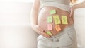 Concept of choosing baby name. cropped shot of pregnant woman with question marks on paper stickers on tummy Royalty Free Stock Photo