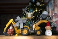 toy bulldozer - excavator, gift box, figurine of Santa Claus, snowman against of a decorated Christmas tree Royalty Free Stock Photo