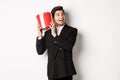 Concept of christmas holidays, celebration and lifestyle. Image of attractive man in black suit, shaking present to