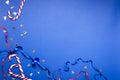 Concept of Christmas time.Candy canes, shine blue and red ribbons, confetti on the dark blue surface Royalty Free Stock Photo