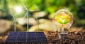 concept clean energy and saving power in nature. solar panel with wind turbine. small tree and lightbulb Royalty Free Stock Photo
