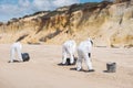 Concept: Cleaning the coast. Group of unrecognizable people. Workers with personal protective equipment cleaning the beach after a Royalty Free Stock Photo