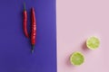 Concept of combination of different tastes in the cuisine.Chilli paper on violet background and lime on pink one.Top view shot wit Royalty Free Stock Photo