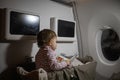 Concept of comfortable flight with infant. little cute toddler sitting in a bassinet and reading a book Royalty Free Stock Photo