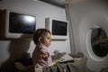 Concept of comfortable flight with infant. little cute toddler sitting in a bassinet and reading a book Royalty Free Stock Photo