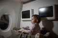 Concept of comfortable flight with infant. little cute toddler sitting in a bassinet and reading a book Royalty Free Stock Photo