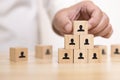 Hand place wooden blocks set to organization chart with people icon.