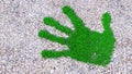 Green grass handprint on gravel background