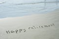 HAPPY RETIREMENT handwritten text in sand on a beach with waves in an exotic island for summer, ocean, sea