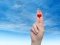 Human or female hands with two fingers painted with a red heart and smiley faces over cloud blue sky Royalty Free Stock Photo