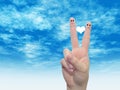 Human or female hands with two fingers painted with a red heart and smiley faces over cloud blue sky Royalty Free Stock Photo