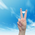 Human or female hands with two fingers painted with a red heart and smiley faces over cloud blue sky Royalty Free Stock Photo