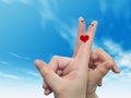 Human or female hands with two fingers painted with a red heart and smiley faces over cloud blue sky Royalty Free Stock Photo