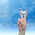 Human or female hands with two fingers painted with a red heart and smiley faces over cloud blue sky Royalty Free Stock Photo