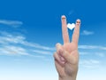 Human or female hands with two fingers painted with a red heart and smiley faces over cloud blue sky Royalty Free Stock Photo