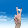 Human or female hands with two fingers painted with a red heart and smiley faces over cloud blue sky Royalty Free Stock Photo