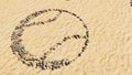 Stones on beach sand handmade symbol shape, golden sandy background, ball sign