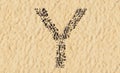 Stones on beach sand handmade symbol shape, golden sandy background, sign of Y
