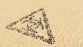 Stones on beach sand handmade symbol shape, golden sandy background, toxic icon