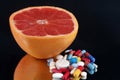 Half grapefruit with a mixture of drugs close-up on black background Royalty Free Stock Photo