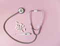 Concept control your health. Stethoscope thermometer and pills with place for text top view on a pink background Royalty Free Stock Photo