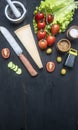 Concept of cooking a healthy salad with cherry tomatoes, parmesan cheese, seasonings and spices, on black rustic wooden backgrou Royalty Free Stock Photo