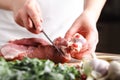 The concept of cooking meat. The chef, the butcher, cuts raw meat with beef, lamb, veal, holding a knife in his hand, on a wooden Royalty Free Stock Photo