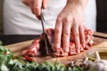 The concept of cooking meat. The chef, the butcher, cuts raw meat with beef, lamb, veal, holding a knife in his hand, on a wooden Royalty Free Stock Photo