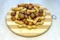 Close-up of assorted nuts: hazelnuts, peanuts, brazil nuts (macadamia) on a round bamboo board.