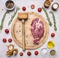 Concept cooking pork steak hammer for meat, seasoning, rosemary, parsley, oil and salt, are laid out around a wooden cutting board Royalty Free Stock Photo