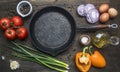 Concept of cooking scrambled eggs with tomatoes, green onions, bell pepper and seasonings on vintage frying pan, around lie ingr Royalty Free Stock Photo