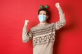 Concept of coronavirus, winter holidays and social distancing. Image of excited and happy man in medical mask and