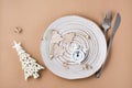 Concept Countdown on Christmas night. Table setting. Alarm clock and Christmas decorations on a plate on a beige background. Top Royalty Free Stock Photo