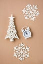 Concept Countdown on Christmas night. White alarm clock, decorative Christmas tree and snowflakes on beige cardboard. Top and