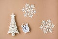 Concept Countdown on Christmas night. White alarm clock, decorative Christmas tree and snowflakes on beige cardboard. Top view