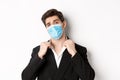 Concept of covid-19, business and social distancing. Image of confident handsome man in trendy suit and medical mask