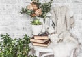 Concept of a cozy home. Old chair, stack of books, knitted plaid, teddy bear toy, succulent flower, dry eucalyptus`s branches on