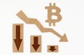 The concept of a crisis in the economy. On a white surface, a graph with down arrows and a bitcoin symbol. Royalty Free Stock Photo