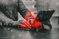 Concept cybersecurity alert. A hacker is working with a laptop. Red alert symbol with digital noise and binary code effects